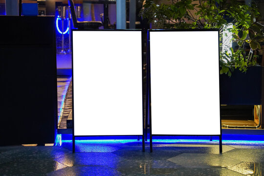 Blank white outdoor advertising stand or sandwich boards mock up template placed by an outdoor dinning area of a restaurant