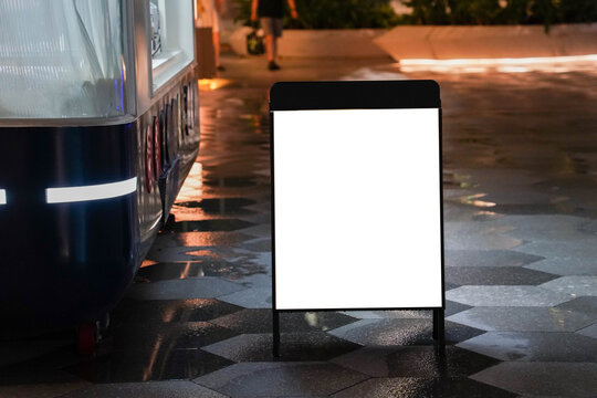 Blank white outdoor advertising stand or sandwich boards mock up template placed by an outdoor dinning area of a restaurant