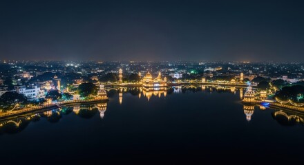 Fototapeta premium A peaceful lakeside city glows at night, with illuminated buildings reflecting in the calm water.