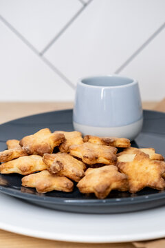 Sweet snack. Cookies plate. Star shape cheese treat served on plate with ceramic cup at kitchen table. Culinary background free space.