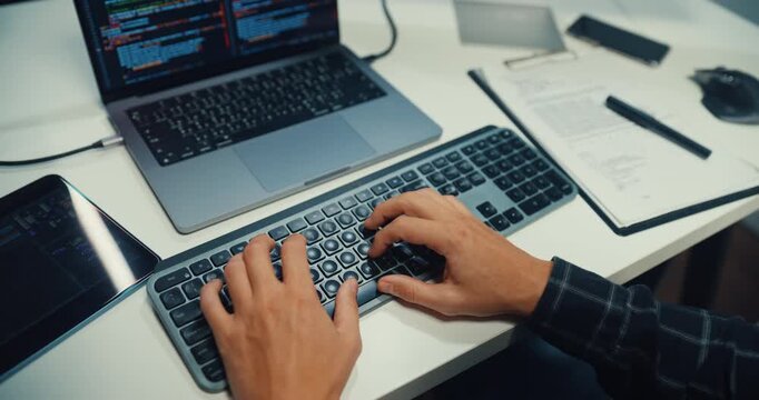 Close up young Caucasian male programmer writes code using multiple screens in home office workspace. AI development, cybersecurity, network database system, software engineering, remote tech startup.