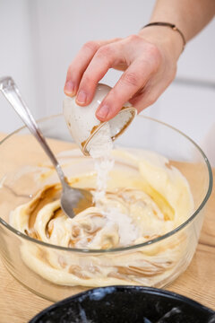 Home cooking. Adding ingredient. Female chef hand pouring measuring sugar portion in glass bowl with sweet caramel cream pastry mass.