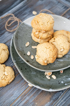 Baked cookies. Tasty food. Golden round treats served on rustic plate with scattered peanut ingredient on wooden table background.