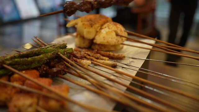 Slow Motion of Picking Up a Kebab from a Platter with Grilled Green Beans, Mantou, and Meat Skewers