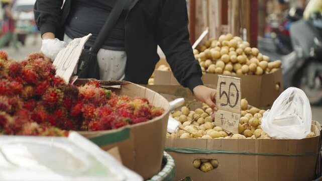 Vendor Arranging Price Tags at a Langsat Stall in a Local Market