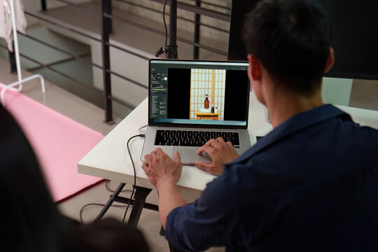 Photographer editing product photos on laptop in studio for post production