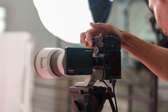 Photographer hand operating camera on tripod in photo studio