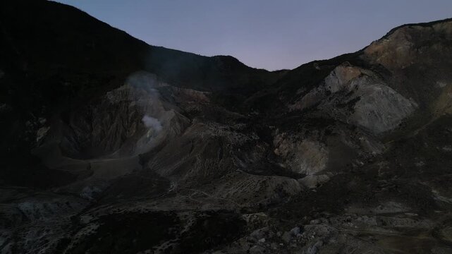 4k Drone video footage of the active crater of Mount Papandayan featuring rugged cliffs and sulfur-rich steam rising from volcanic vents in West Java, Indonesia.
