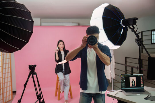 Photographer taking pictures of female model in photography studio