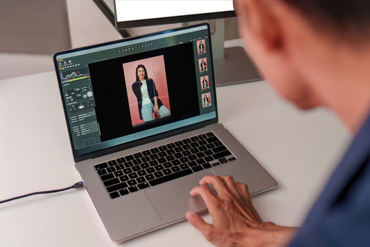 Photographer editing portrait photo on laptop computer at studio workspace