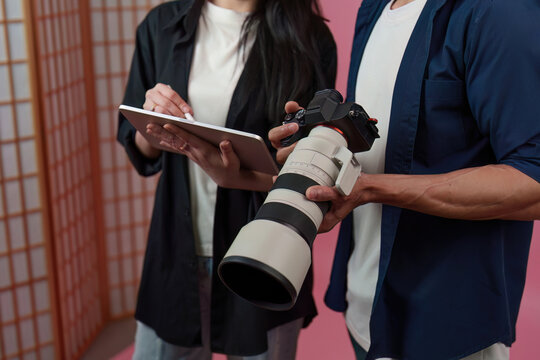 Photographer and assistant reviewing shot on tablet in creative photo studio
