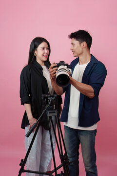 Asian photographer showing photos on camera to female model in studio