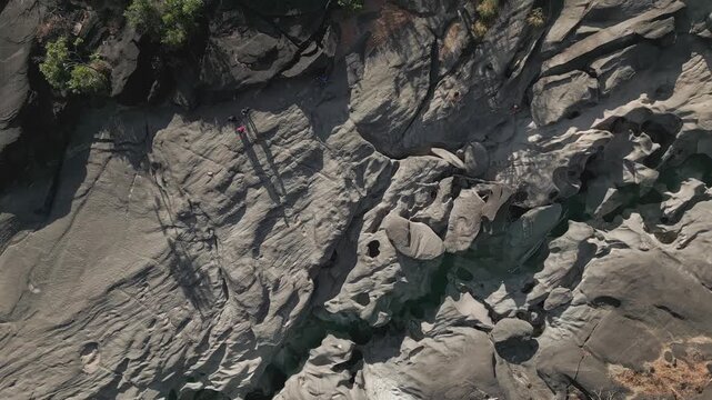 Quartzite bedrock sculpted by the Sao Miguel River dominates Vale da Lua, Alto Paraiso de Goias, Chapada dos Veadeiros, Goias, Brazil, top-down drone spin ascending.
