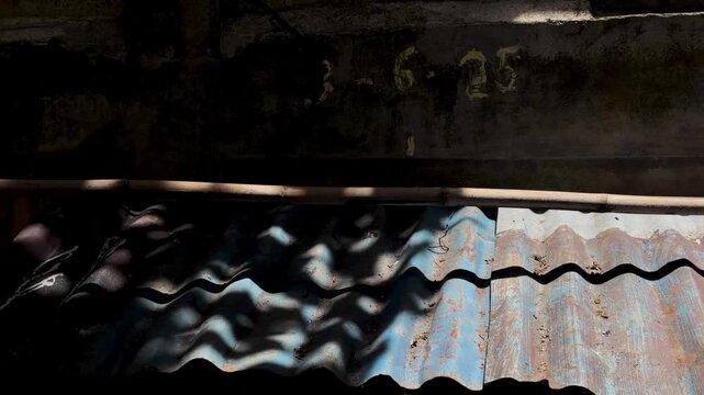 Rustic corrugated metal roof texture with dappled sunlight creating wavy shadows