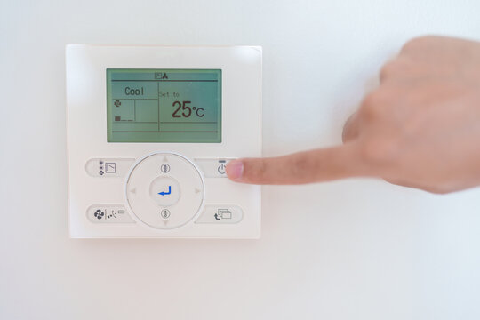 operating and adjusting Air conditioner temperature by remote control in home. Hand holding remote control and setting comfortable temperature on climate system in office or apartment. hot and cool