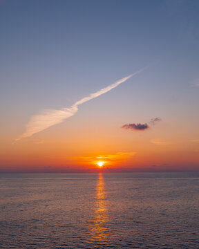 Vivid ocean sunset beneath a long diagonal cloud formation