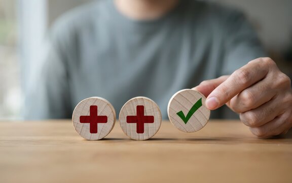 Hand selecting a green checkmark from three wooden circles with red crosses against a blurred background symbolizing choice and decision making