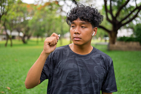 African American mixed race man with wireless earbuds listening to music while warming up before jogging in urban park.