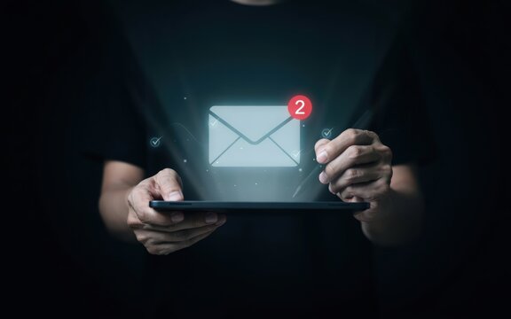 Person holding tablet displaying glowing email notification with two unread messages during digital communication