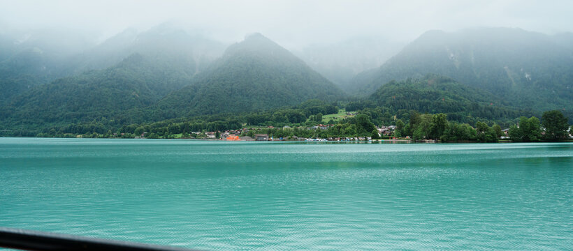 Scenic Cruise View of Lake Brienz from a Passenger Boat with Swiss Chalets Village, Alpine Mountains, Turquoise Lake and Mist, Switzerland. Picturesque Landscape and Famous Europe Travel Destination