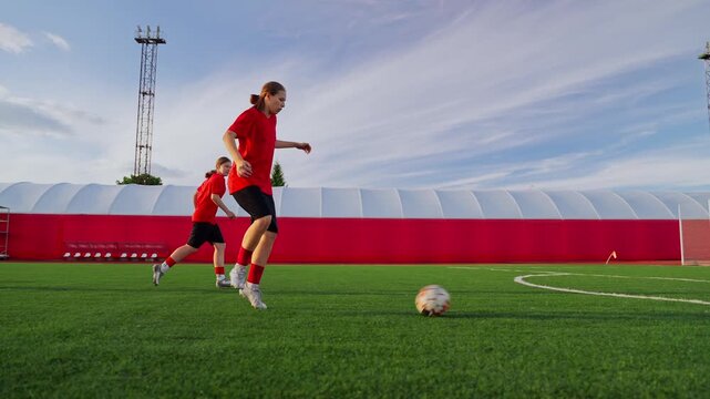 Intensive womens soccer training session on modern outdoor field with passing drills, agility exercises, and teamwork development in bright daylight conditions