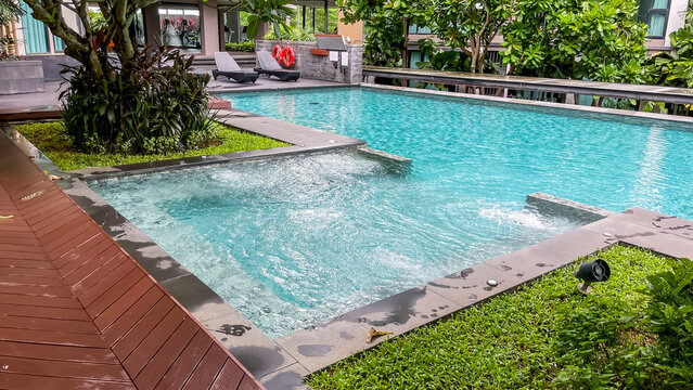 An outdoor pool with a whirlpool area on the grounds of a modern residential condominium in Thailand after tropical rain during the monsoon season. The well-maintained grounds, tropical garden.