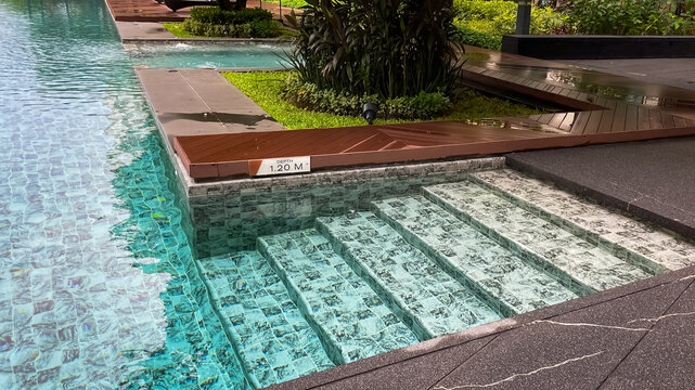 Steps leading into a gently sloping pool at a modern residential condominium in Thailand after a tropical rainstorm during the monsoon season.