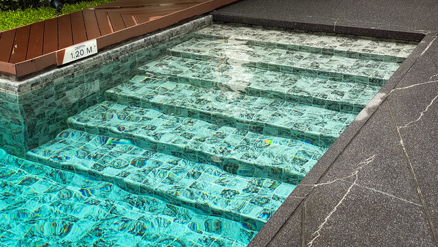 A close-up of the steps of a swimming pool with clear turquoise water in a modern condominium in Thailand.
