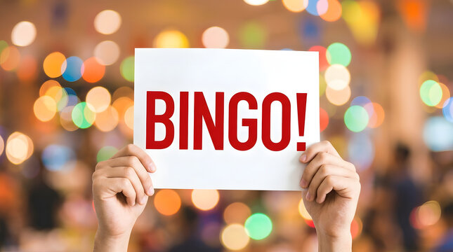 Hands holding a white sign with bold red letters spelling BINGO against a vibrant, blurred bokeh background of colorful lights and festive atmosphere featuring text, word, celebration and event