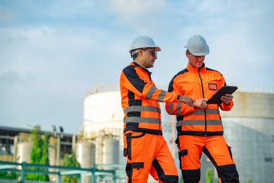 Senior engineer pointing at inspection results on tablet while discussing maintenance tasks with a colleague. Industrial teamwork, engineering consultation, safety management, technical inspection.