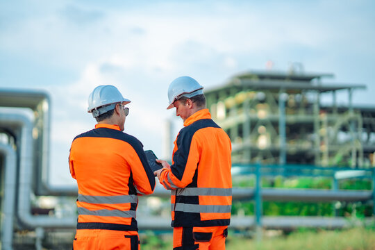 Two engineers observing refinery infrastructure from production during an industrial inspection. Facility monitoring, engineering collaboration, operational planning, energy industry 