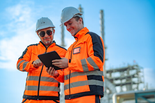 Engineers reviewing inspection results on a digital tablet at a petrochemical facility. Technical collaboration, engineering analysis, preventive maintenance, digital workflow, industrial operations.