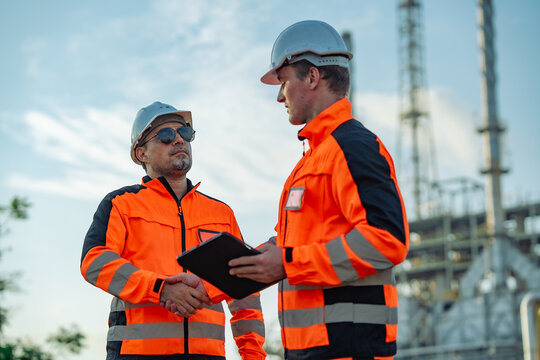 Industrial engineers shaking hands after completing a refinery inspection and maintenance review. Professional partnership, engineering teamwork,  industrial safety, operational excellence.