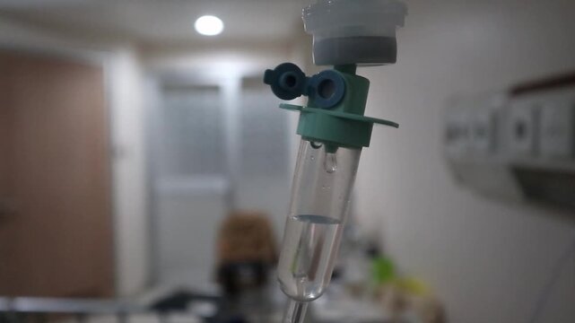 Defocus blur medical IV drip chamber in hospital room, intravenous infusion dripping in patient ward, healthcare and treatment concept.