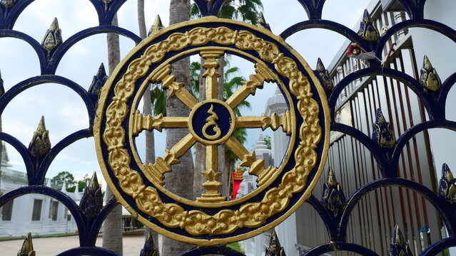 Golden Dharmachakra Wheel of Dhamma Symbol on Wrought Iron Fence