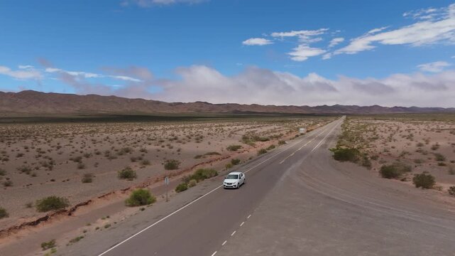 Drone side tracking pullback of car on Recta del Tin Tin highway, aerial