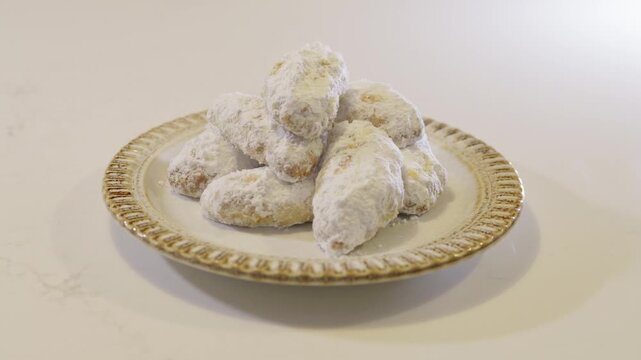 Close-up of traditional Greek shortbread cookies dusted with icing sugar and served on a plate. Freshly baked treats showcasing classic Mediterranean baking and homemade desserts.