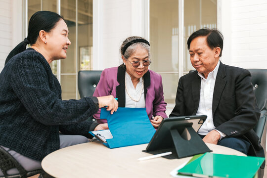 Three adults meet around a table, reviewing documents and a tablet during a friendly financial consultation in a bright office