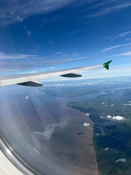 Scenic aerial view point of view from inside commercial airplane window during flight include with plane wing