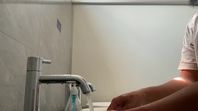 Person with limb difference washing hands under running water for hygiene and infection prevention