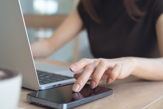 Close up, Business woman working on laptop computer and using smartphone, surfing the internet at office