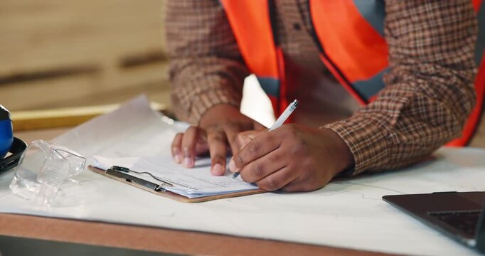Person, hands or carpenter writing with clipboard in warehouse for wood production or checklist. Carpentry, builder or taking notes with documents for timber project, lumber plan or distribution