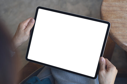 Mockup, woman using digital tablet with blank white screen during working at coffee shop, close up. Mockup tablet for online marketing or web template