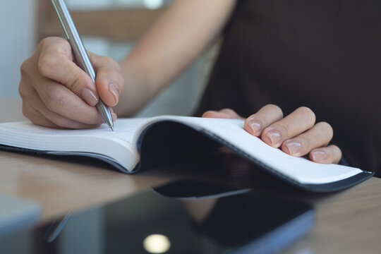 Close up, business woman hand writing notes or planning agenda, appointment and schedule in diary, journal or event planner at corporate office