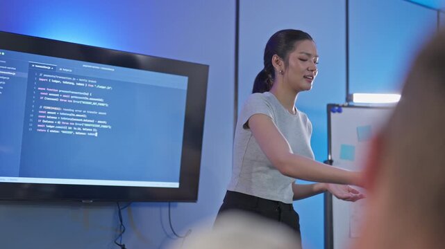 Asian female developer presents code review insights and feedback to team, demonstrating technical leadership and collaborative code discussion with colleagues.
