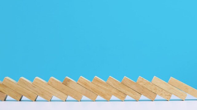 Satisfying wooden block domino chain reaction sequence creates beautiful pattern on blue background with clean minimalist orderly business strategy