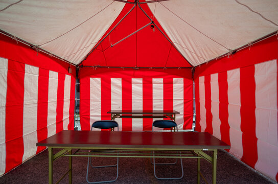 Symmetry view inside a traditional red and white striped event tent with tables and chairs in Japan