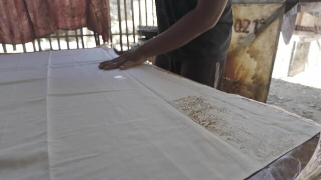 Close Up of Artisan Applying Hot Wax with Copper Batik Stamp on Fabric in Indonesia