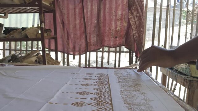 Forward Moving Shot of Artisan Hand Stamping Traditional Batik Fabric in Indonesia