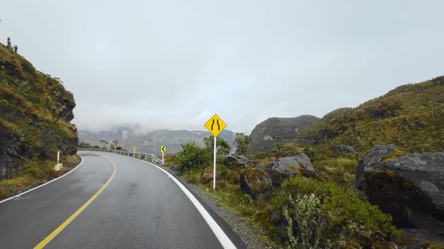 A vehicle POV follows the Murillo&ndash;Manizales road along a mountainside, overlooking vast valleys and distant ranges beneath misty clouds.